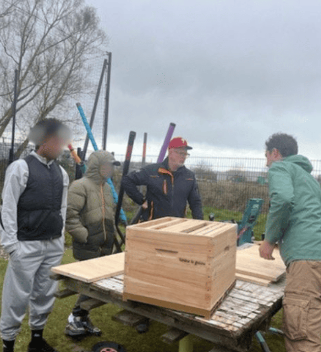Groupe de participants autour d’une ruche pendant une animation abeilles