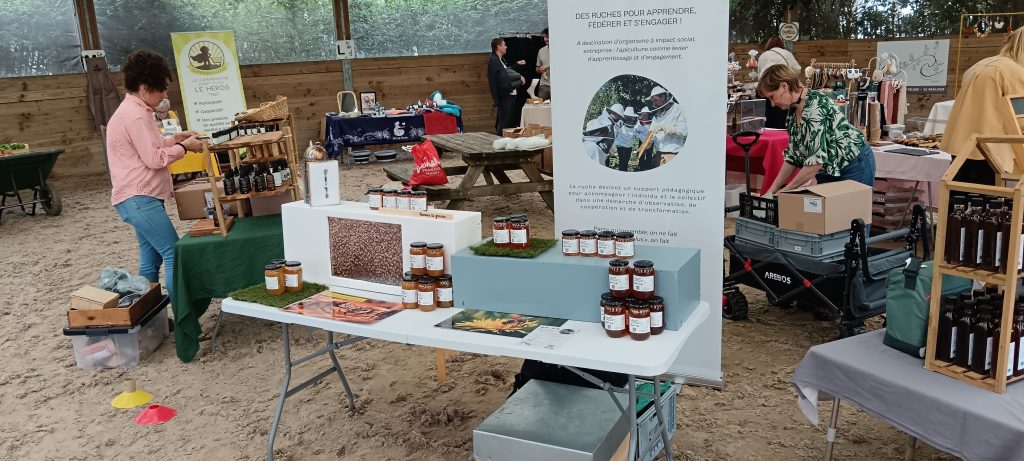 Atelier pédagogique sur les abeilles à Douai : un groupe observe un cadre de ruche avec l’apiculteur