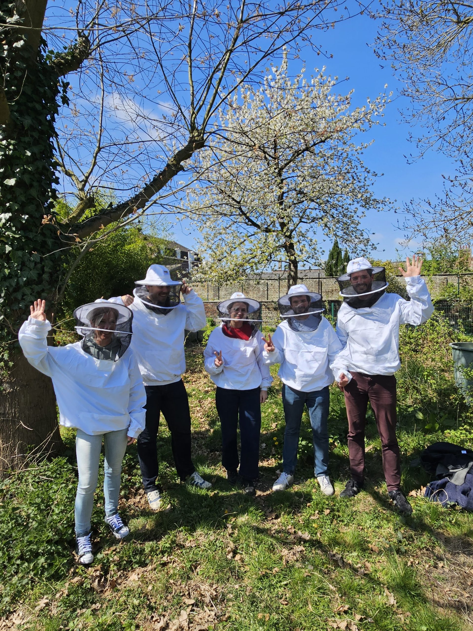 Équipe en tenue d’apiculteur autour d’une ruche pendant un team building abeilles